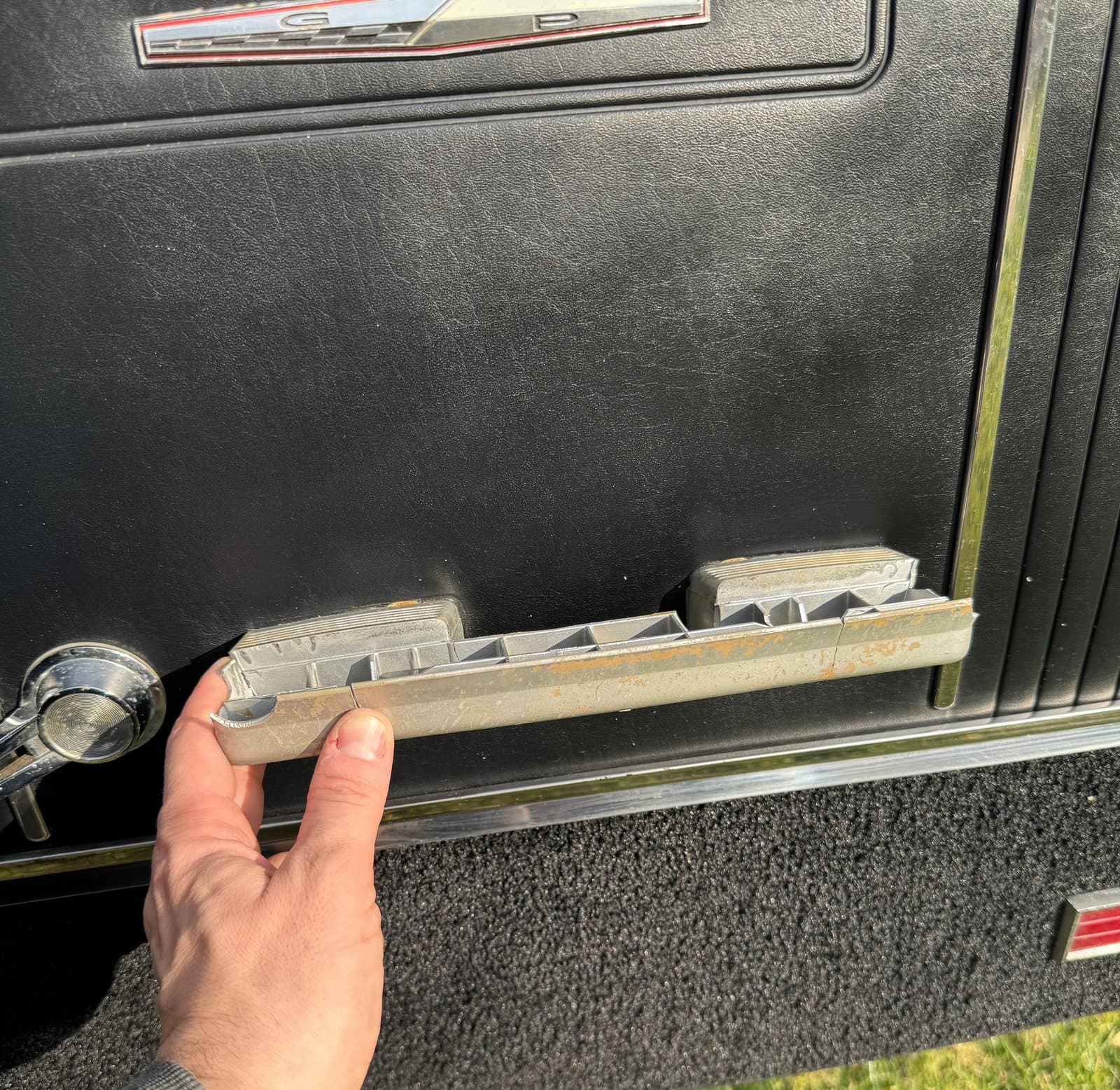 The worn original casting held up to the door panel, the starting point of the whole job.