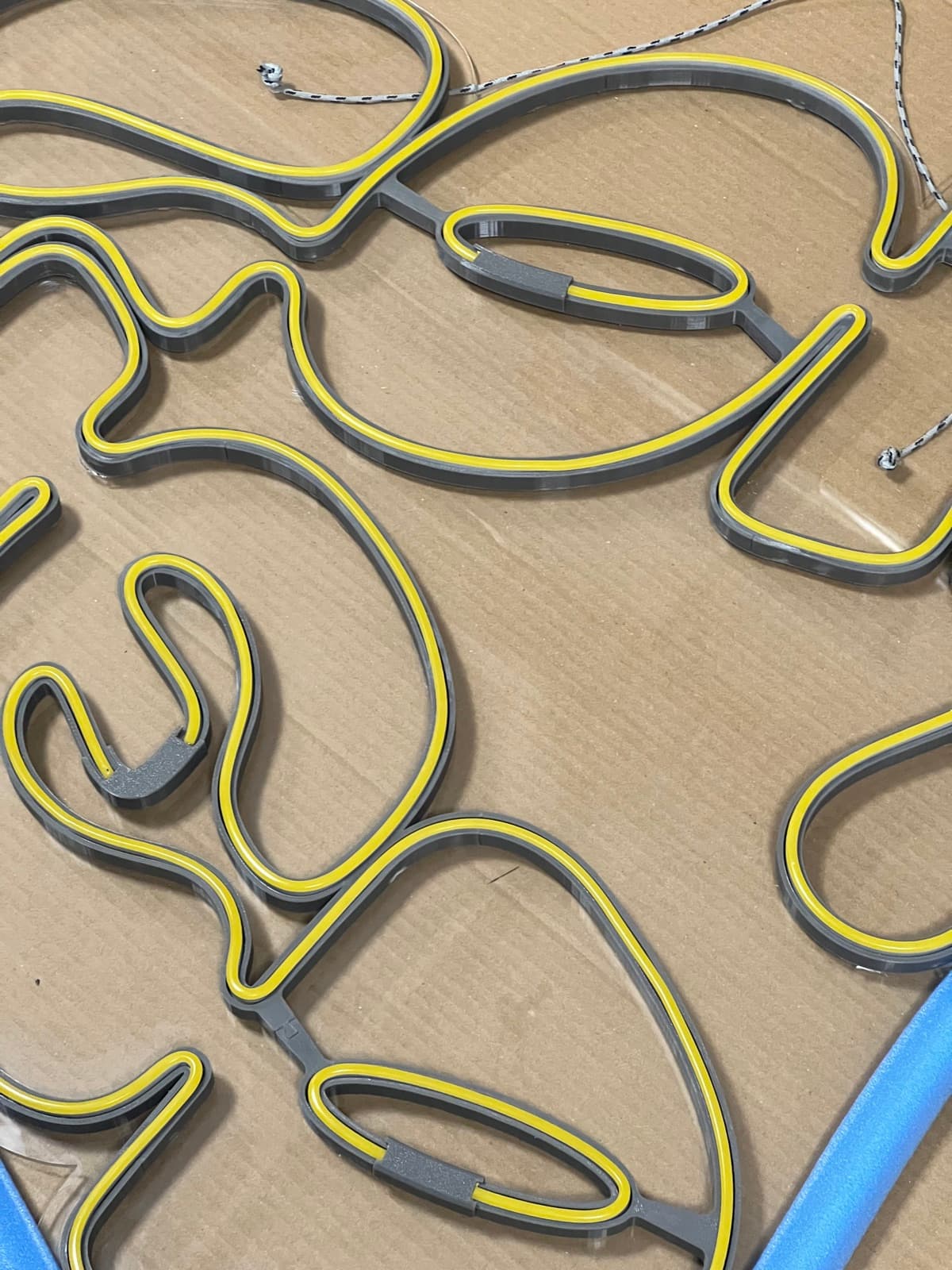 Close-up of yellow LED neon seated in the printed letter channels, laid out on cardboard.