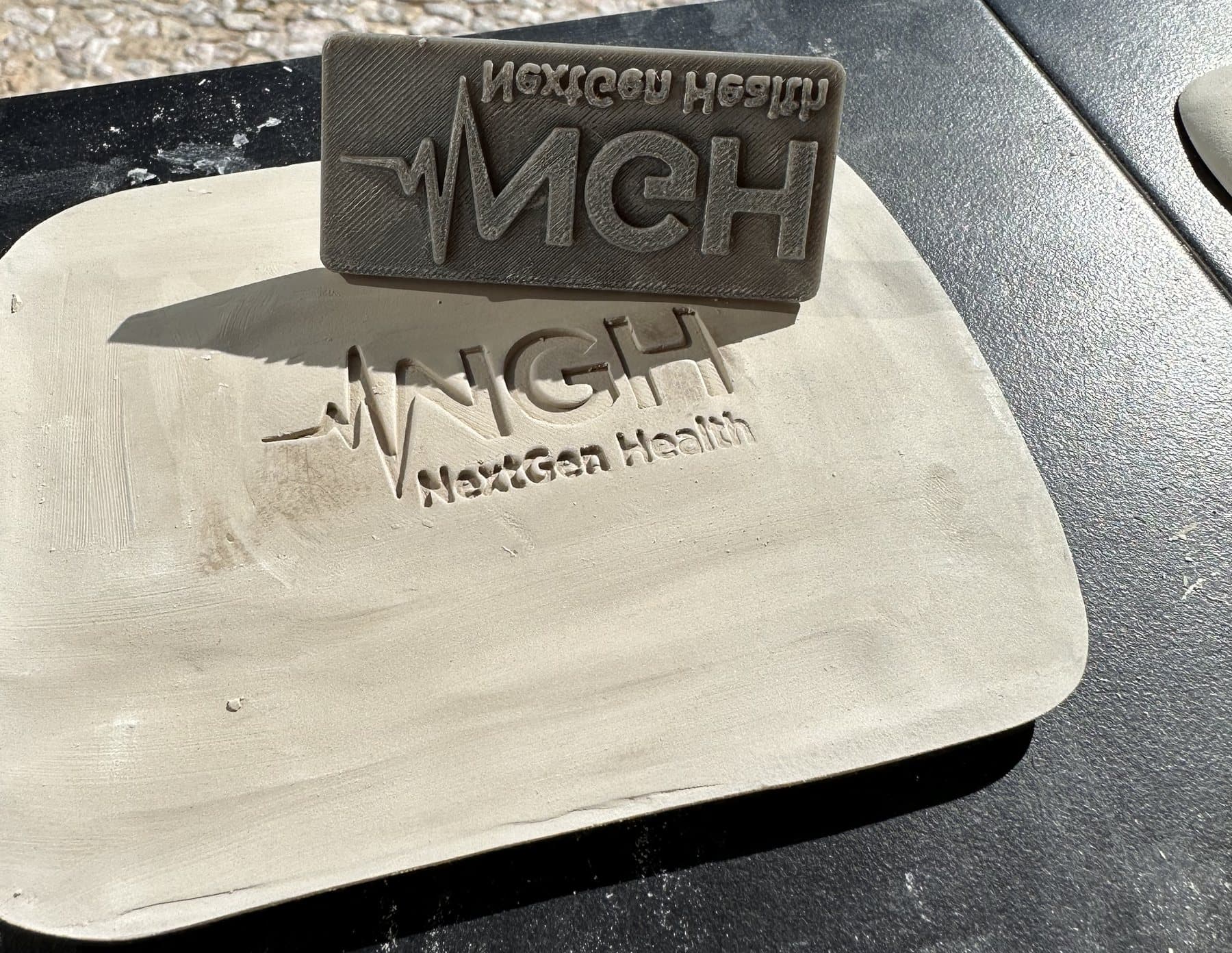The stamp standing on its edge beside the impression: the same logo in negative and positive.
