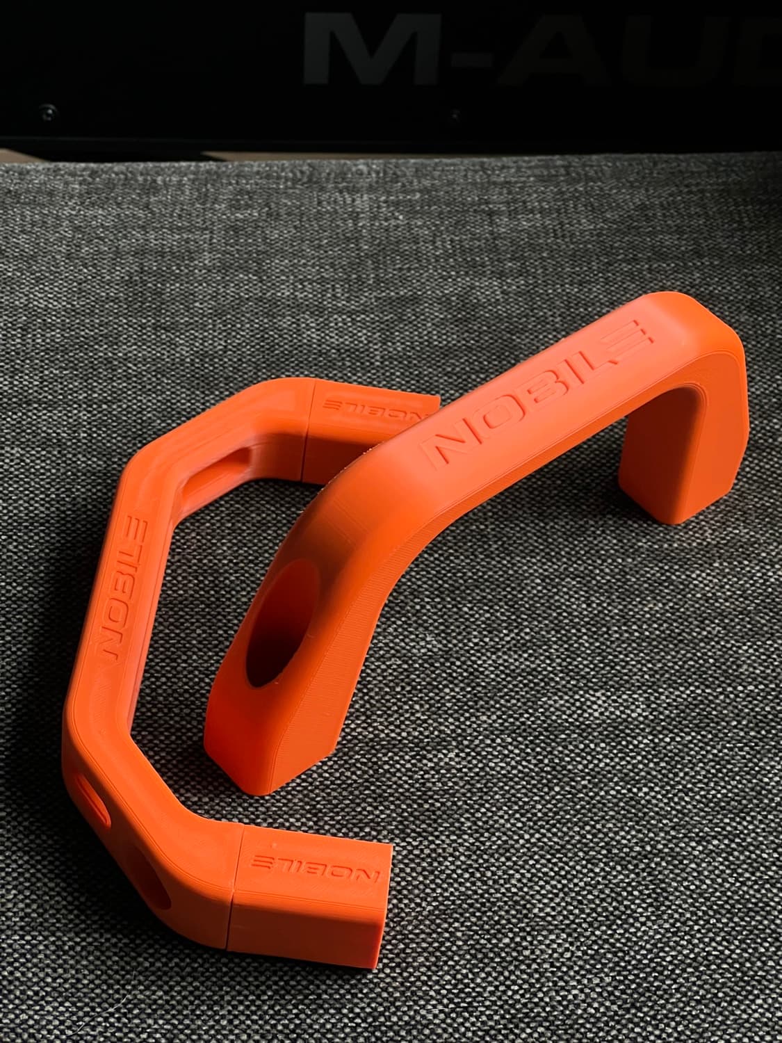 Two PETG-printed Nobile kite handles on textured backing