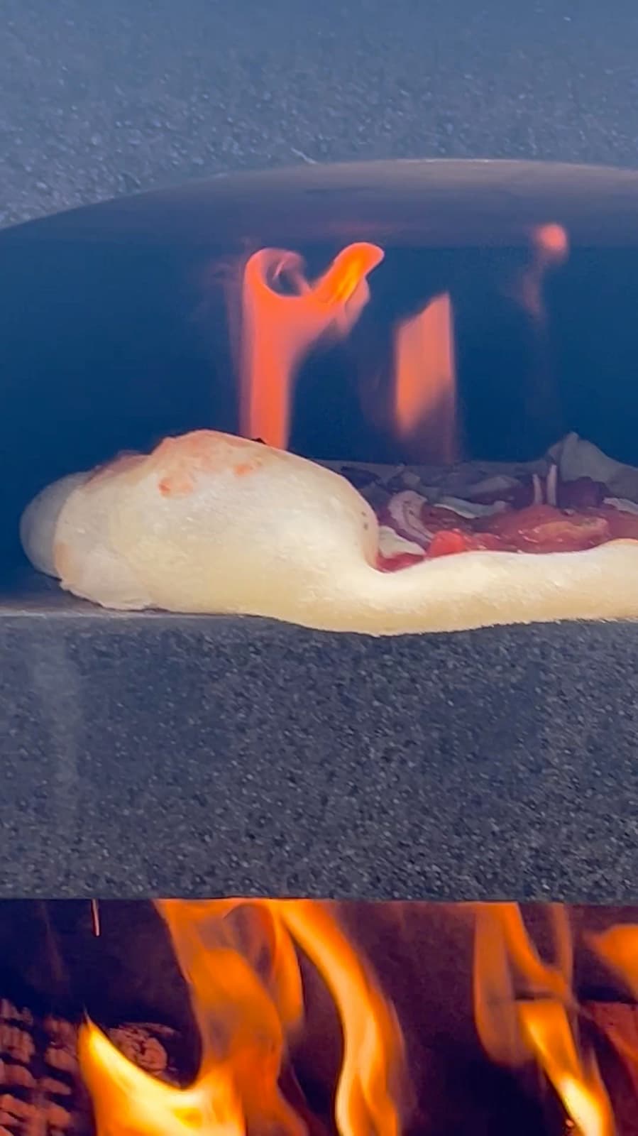 Pizza piecze się między płomieniami w komorze.