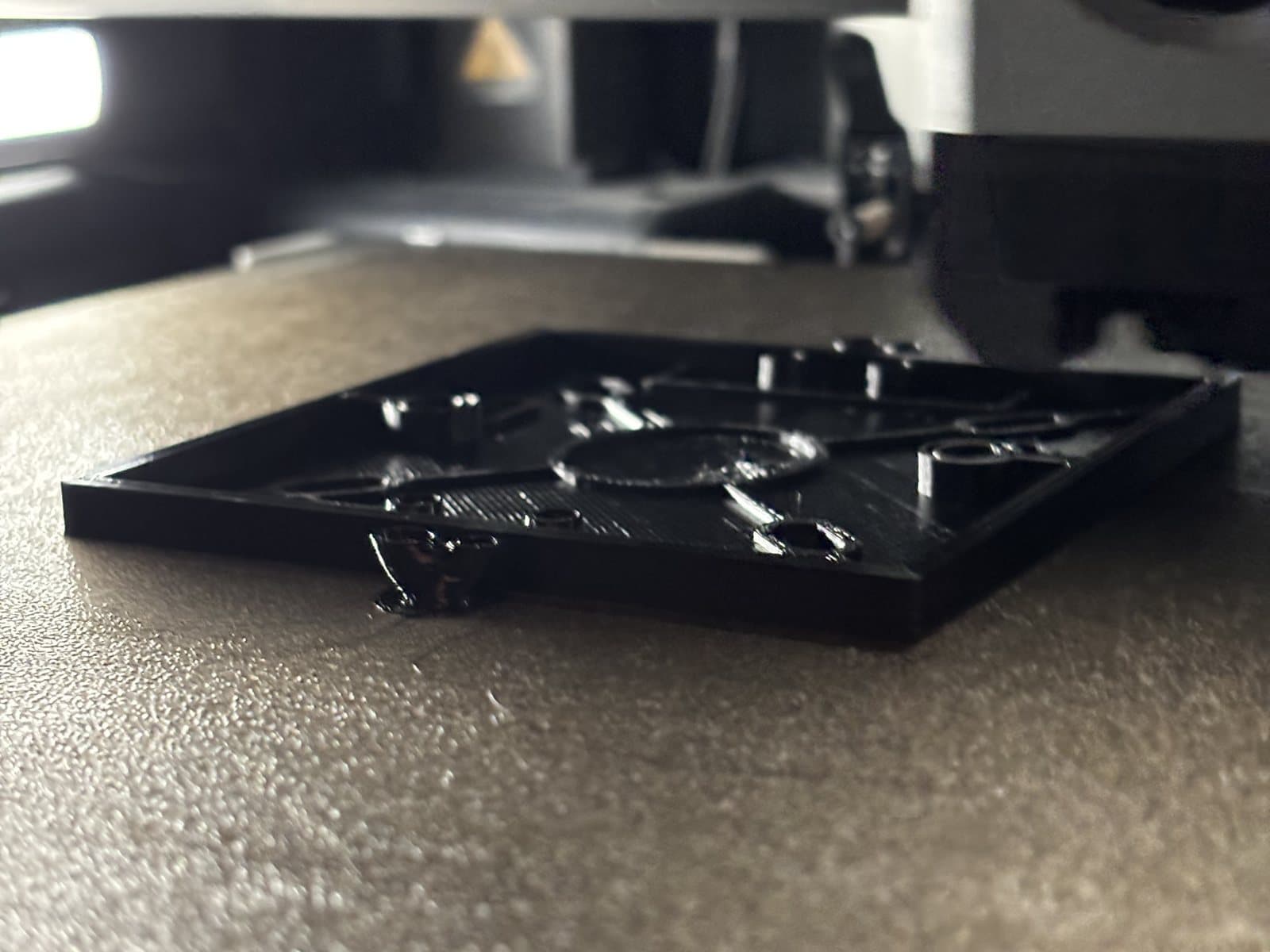 The base of the box on the printer bed: windows, slots and raised lines in the first layers.