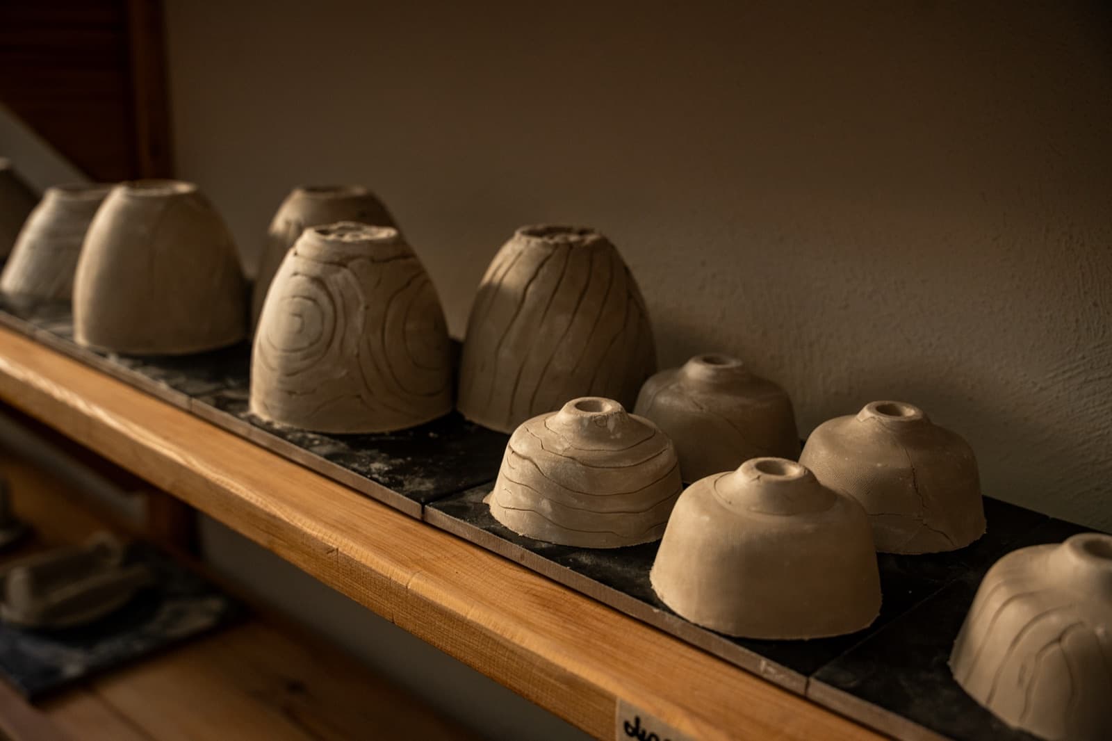 Cast lamp shade forms drying on a workshop shelf
