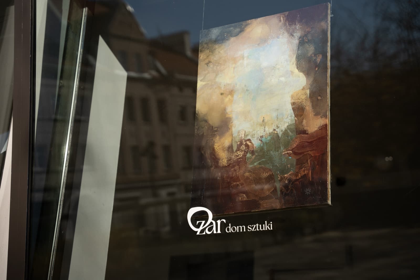 Dom Sztuki Zar storefront window with the venue logo and a painting